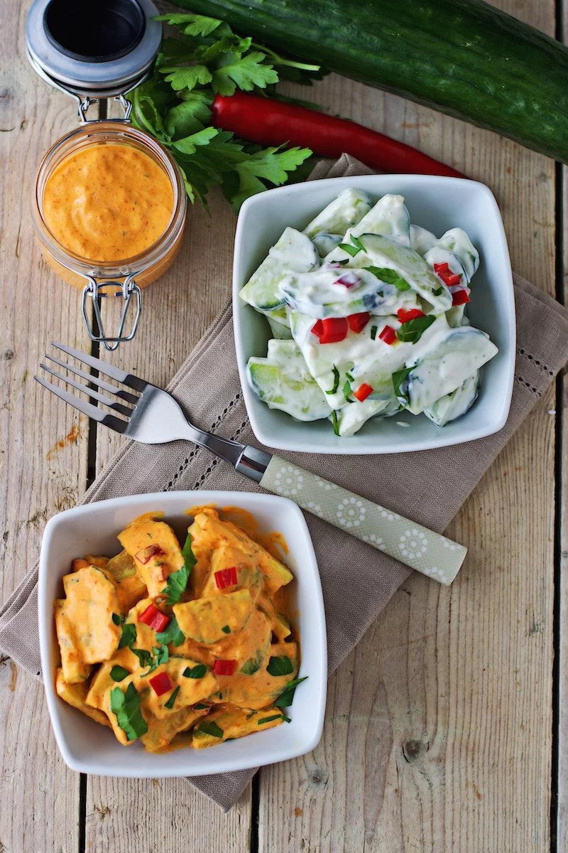 Two small bowls with the differently flavored cucumber salads placed on a decorative cloth.