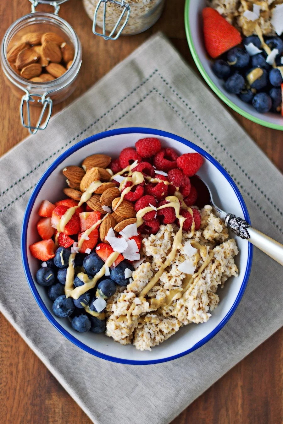 Top view of one Breakfast Bowl with fresh fruits and nuts, with a spoon at the side.