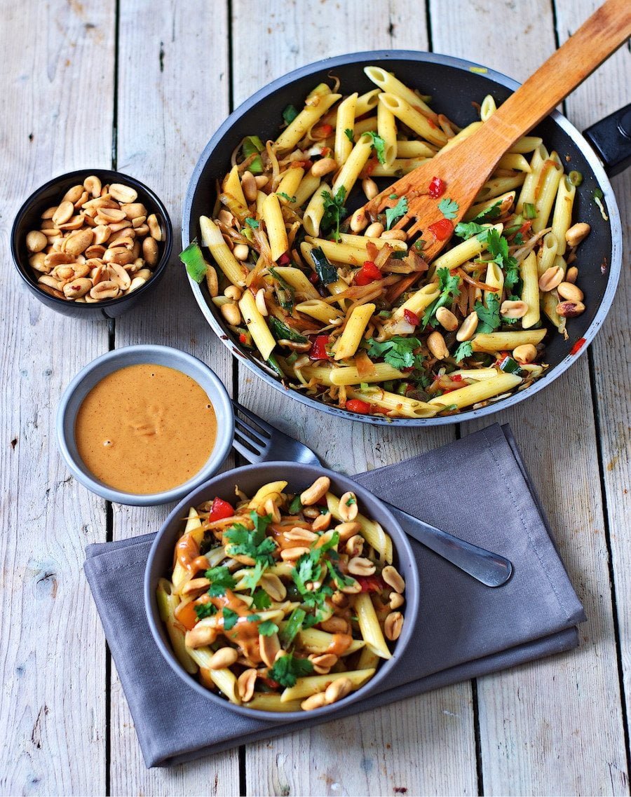 A portion of the Creamy Peanut Pasta in a grey bowl is placed on a decorative towel.