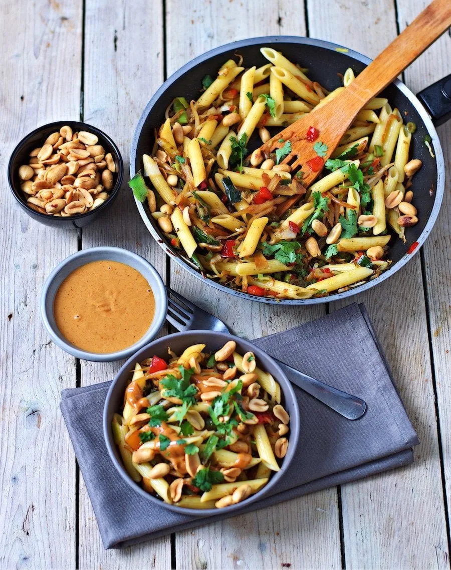 A portion of the Creamy Peanut Pasta in a grey bowl is placed on a decorative towel.