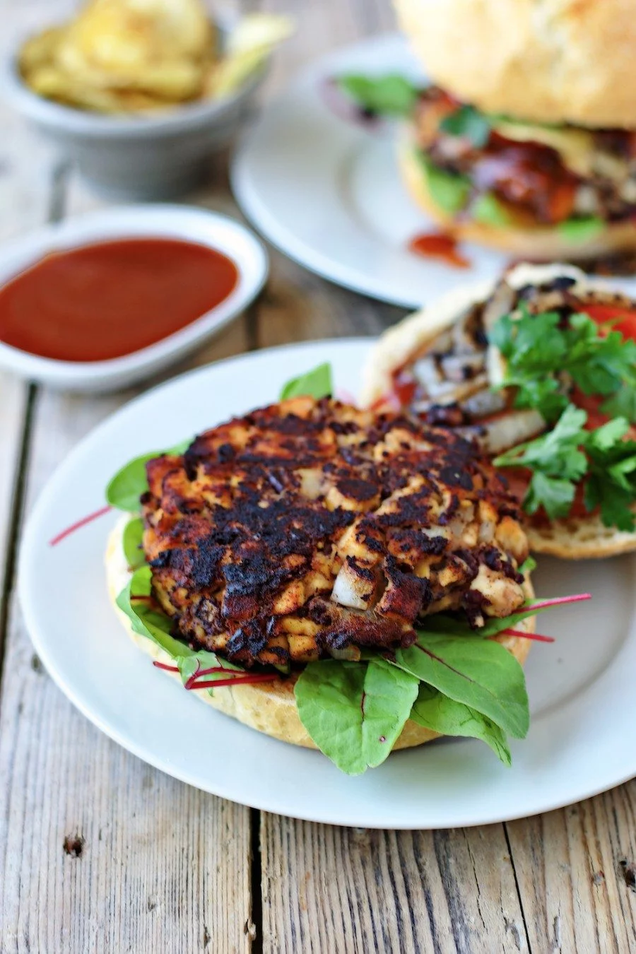 Closeup of a patty of the Vegan Buffalo Burger on a bun, with topping on the side.