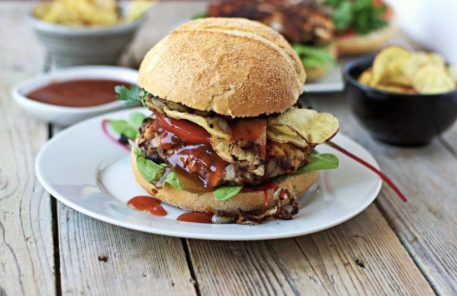 One Vegan Buffalo Burger with a lot of sauce dripping out of it.