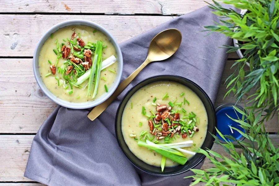 Two bowls of the Leek and Potato Soup, placed on a agre towel, with cutlery.