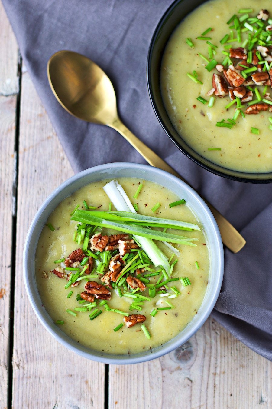 Closeup of the Leek and Potato Soup in a grey bowl, showing the vegetable toppings.