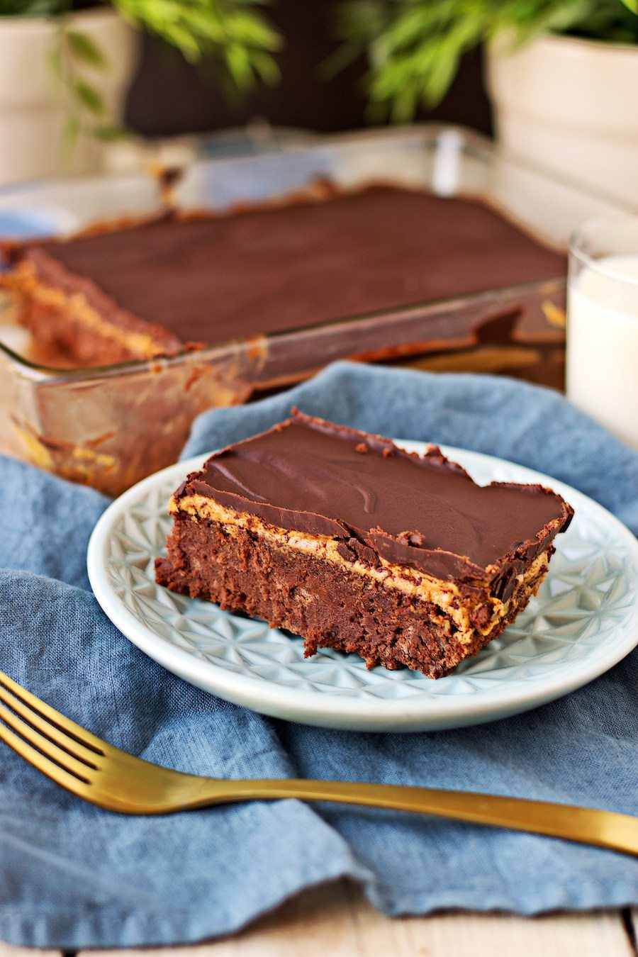 One Vegan Buckeye Brownie on a plate, with the full baking dish visible in the background.