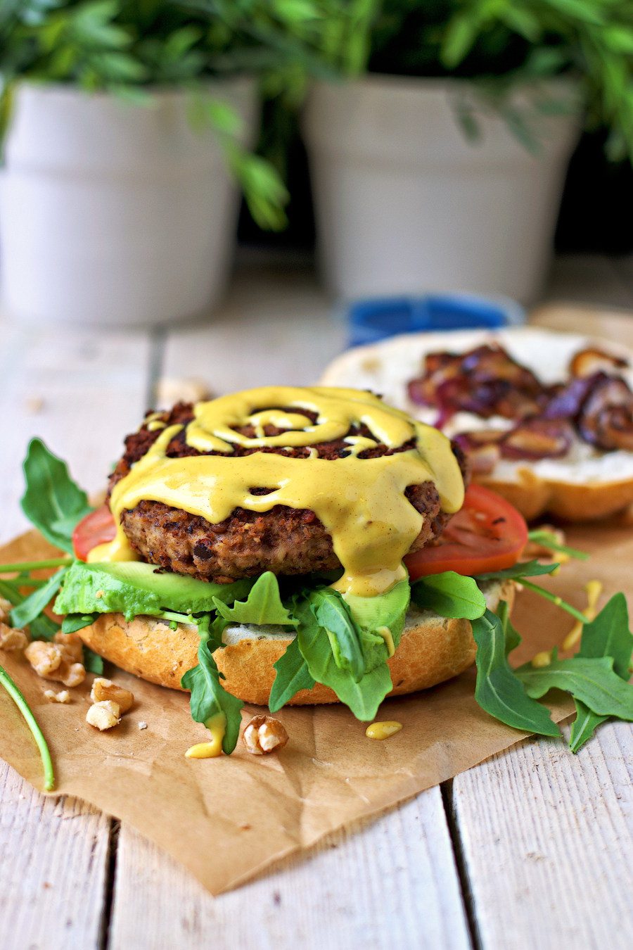 Side view on the open Vegan Lentil Burger with mustard sauce being sprinkled on the patty.