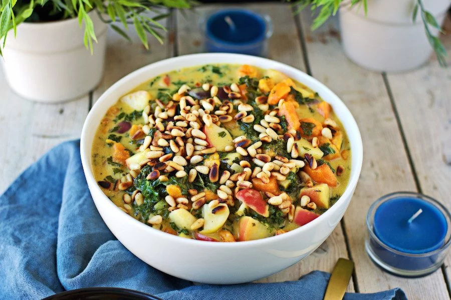 A large bowl of the Vegan Sweet Potato Soup with Kale seen from the side.