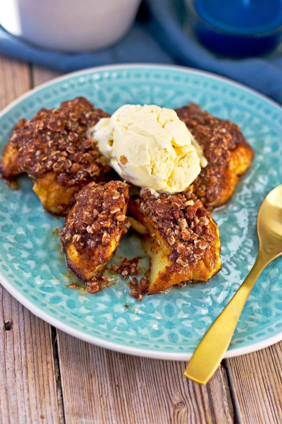 One baked apple is cut open, with ice cream melting on top.