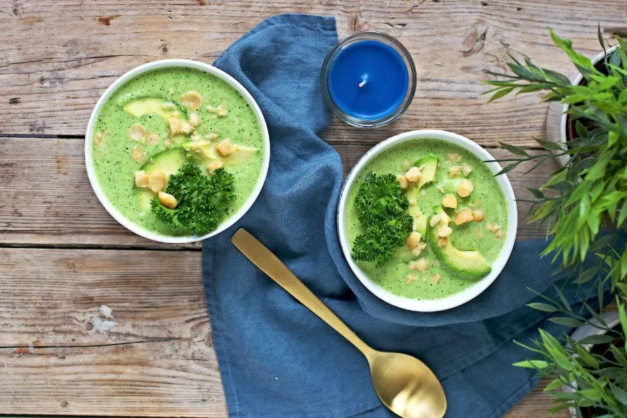 Two bowls of the Detox Broccoli Soup placed on a decorative towel with golden spoon.