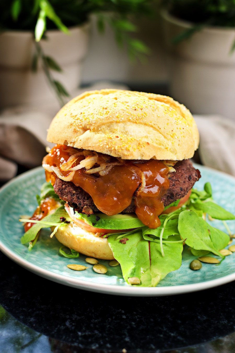 Fully assembled Vegan Black Bean Burger, seen from the side, on a plate.