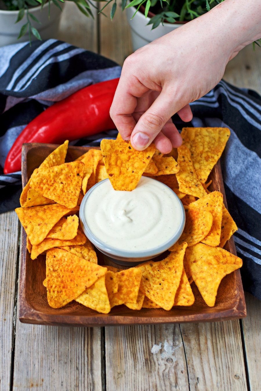 A small bowls with the Vegan Cheese Sauce is placed on a bed to tortilla chips.