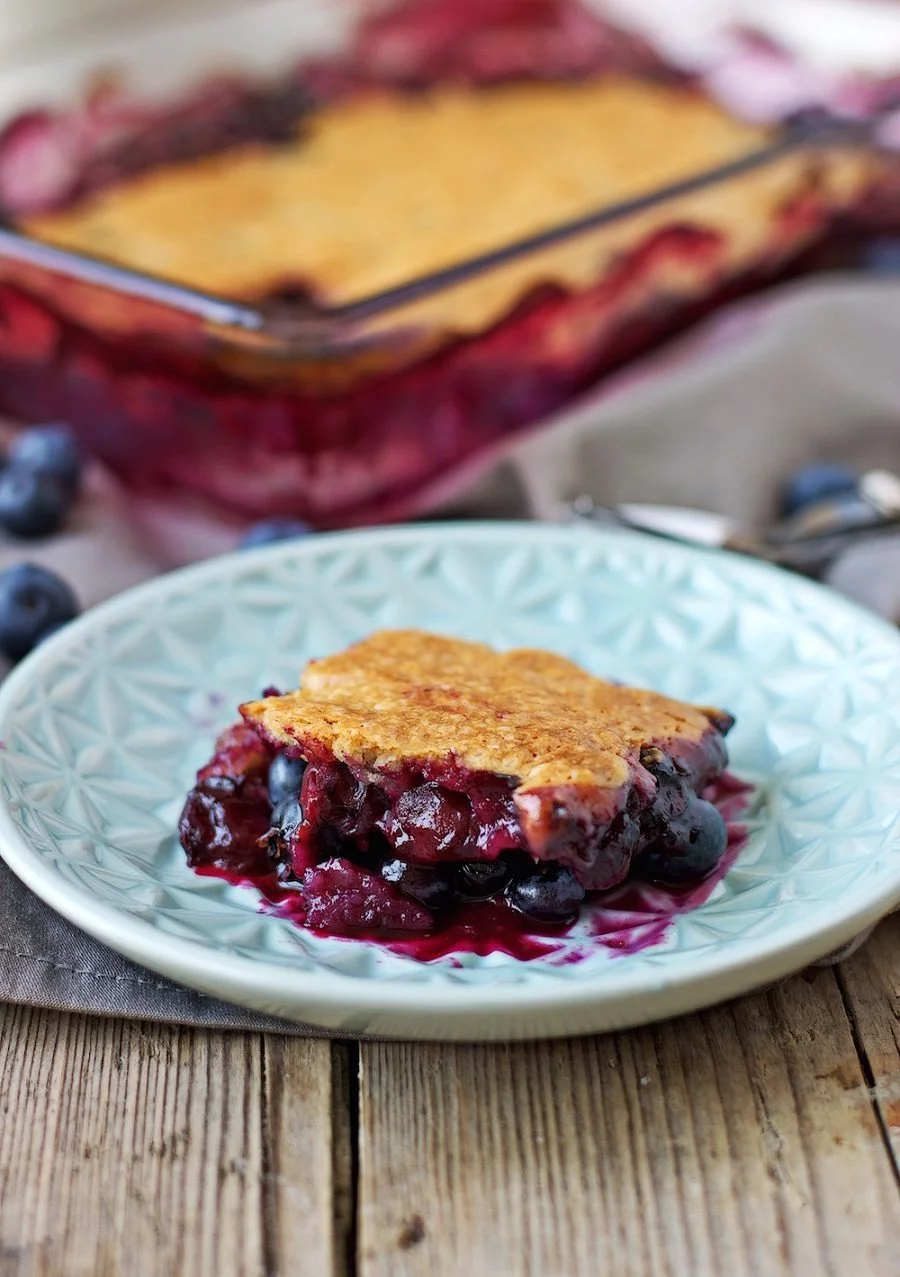 A single piece of the Easy Blueberry Cobbler is placed on a small blue plate, and seen from the side. | #vegan #glutenfree #dessert contentednesscooking.com