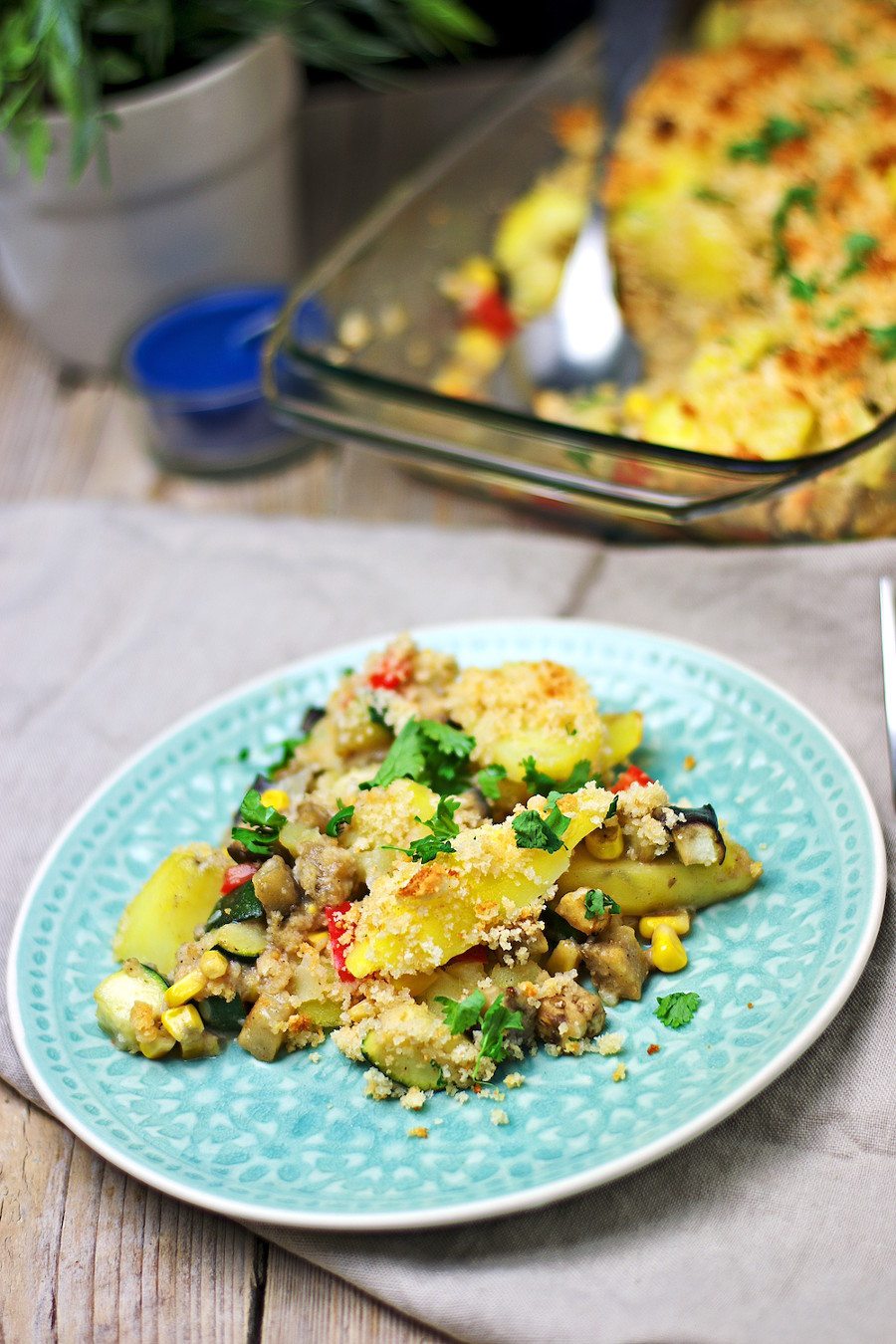 Portion of the Vegan Potato Casserole taken out of the casserole dish in the background.