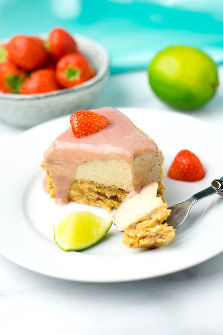 A piece of a slice of the cheesecake is taken off with a fork.