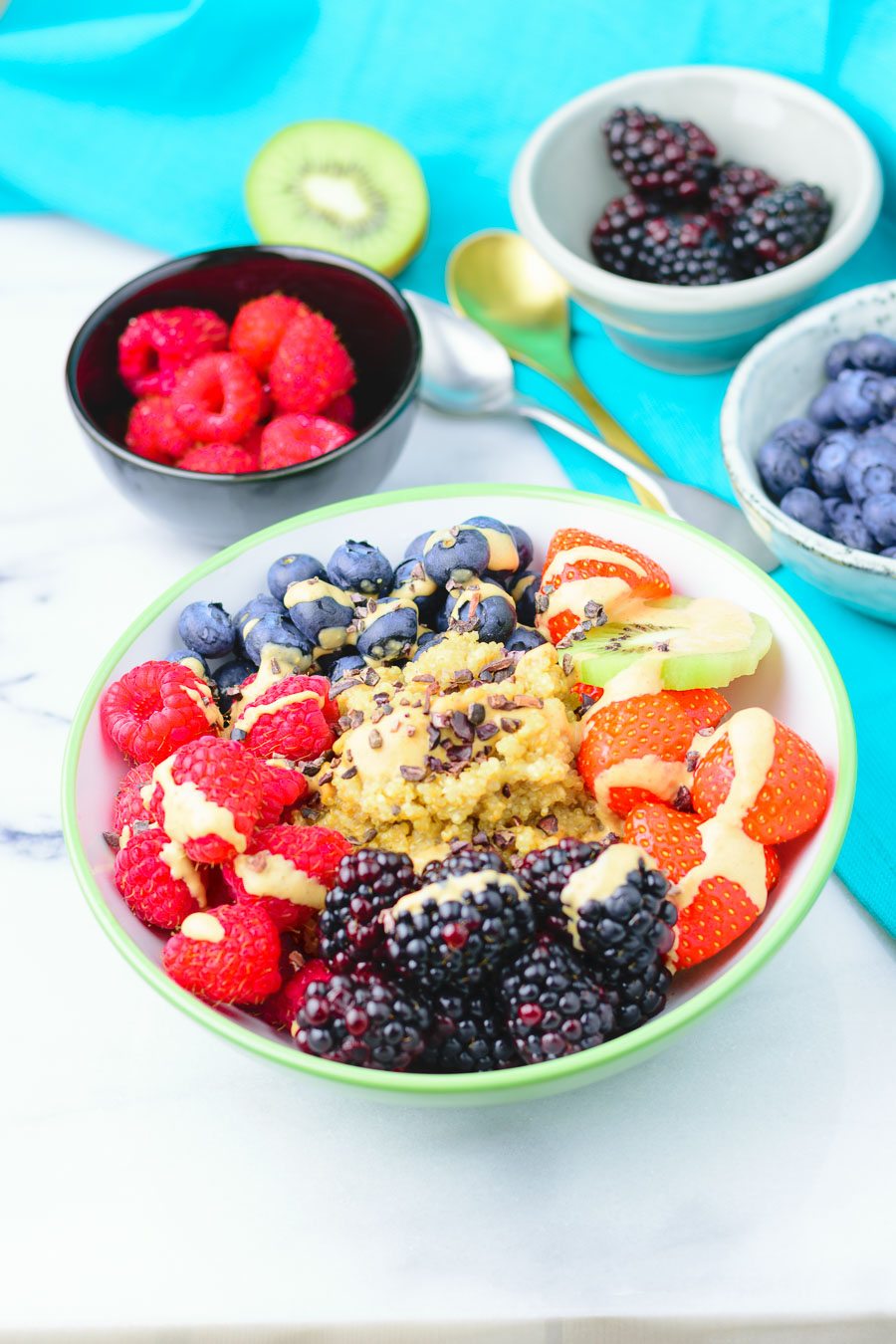 A single Quinoa Breakfast Bowl with all ingredients in sections and sprinkled with sauce.