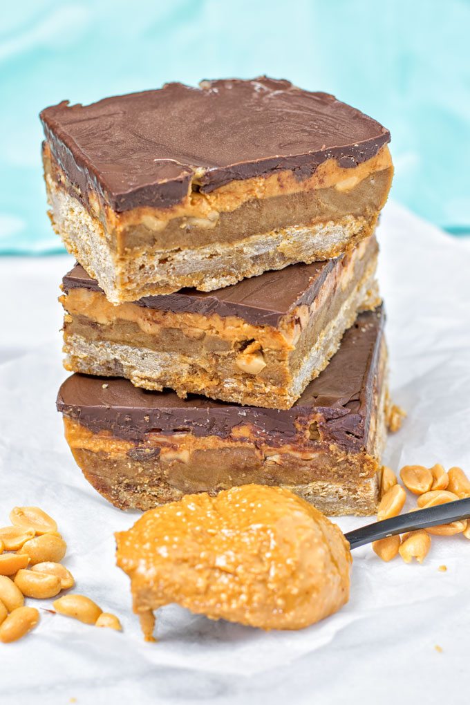 Extra spoon of peanut butter in front of Vegan Snickers Bar stacks.