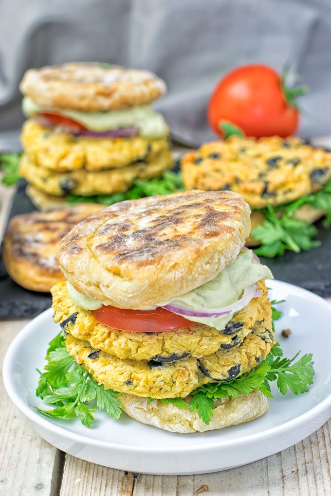 An assembled Mediterranean Vegan Burger with several more in the background.