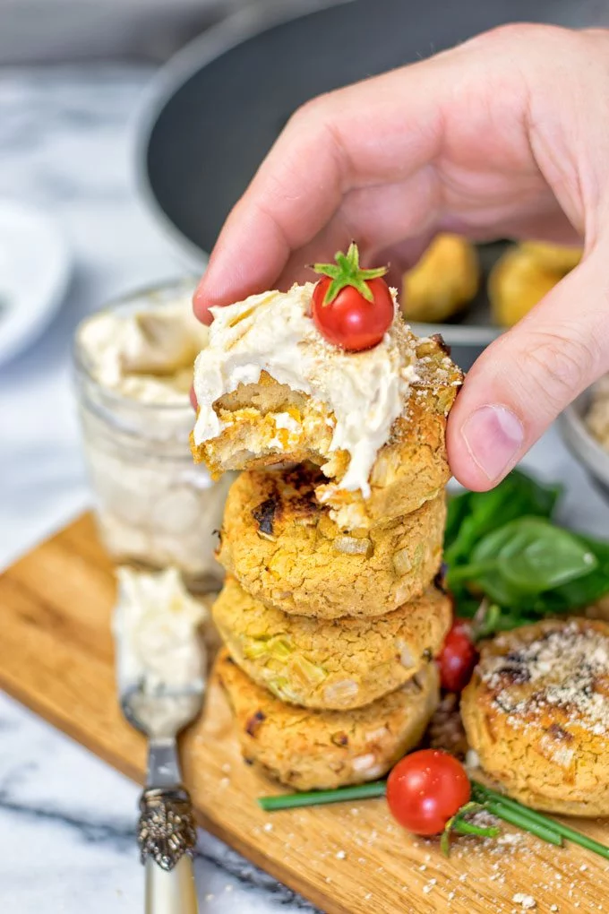 A Roasted Garlic Vegan Cheese Fritter is held in hand, with a bite taken off.