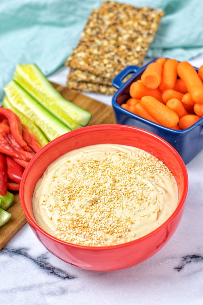 A bowl of the 30 Seconds Best Hummus Recipe with fresh vegetables in the background.