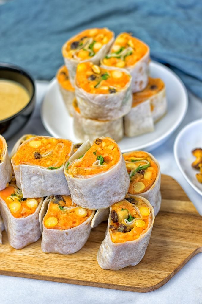 Serving board in front of a plate with the Thai Green Curry Samosa Pinwheels.