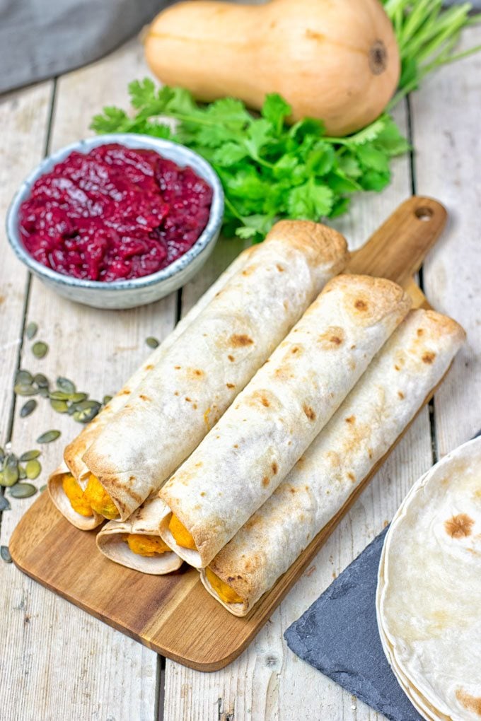 Five Pumpkin Vegan Cream Cheese Taquitos on a wooden board.