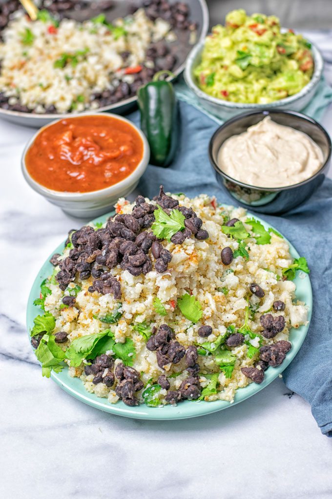 A plate full of the Mexican Fiesta Cauliflower Rice with extra dipping sauces in the background.