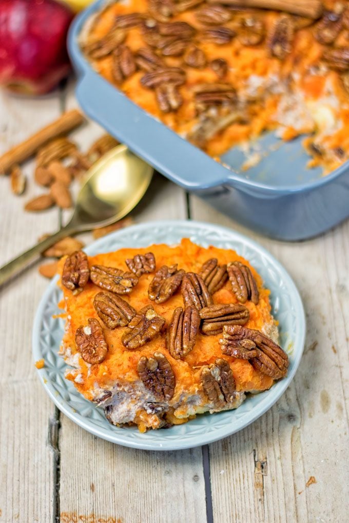 Serving of the Sweet Potato Casserole on a plate with the casserole dish in the background.
