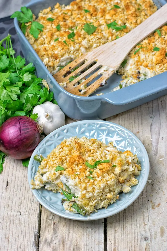 Mashed Cauliflower Green Bean Casserole served on a plate with the casserole dish in the background.