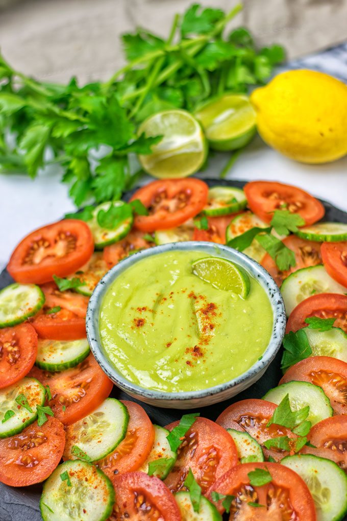 A bowl of the everyday Detox Dipping Sauce served with fresh cucumber and tomato slices.