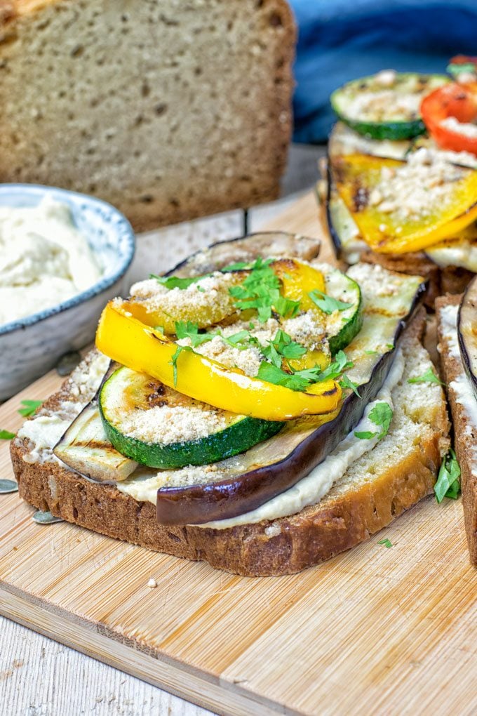 Closeup on a Hummus Homemade Bread sandwich with the cut loaf in the background.