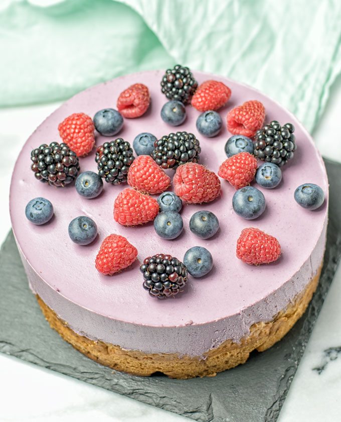A full Berry Smoothie Yoghurt Cake on a black serving plate.