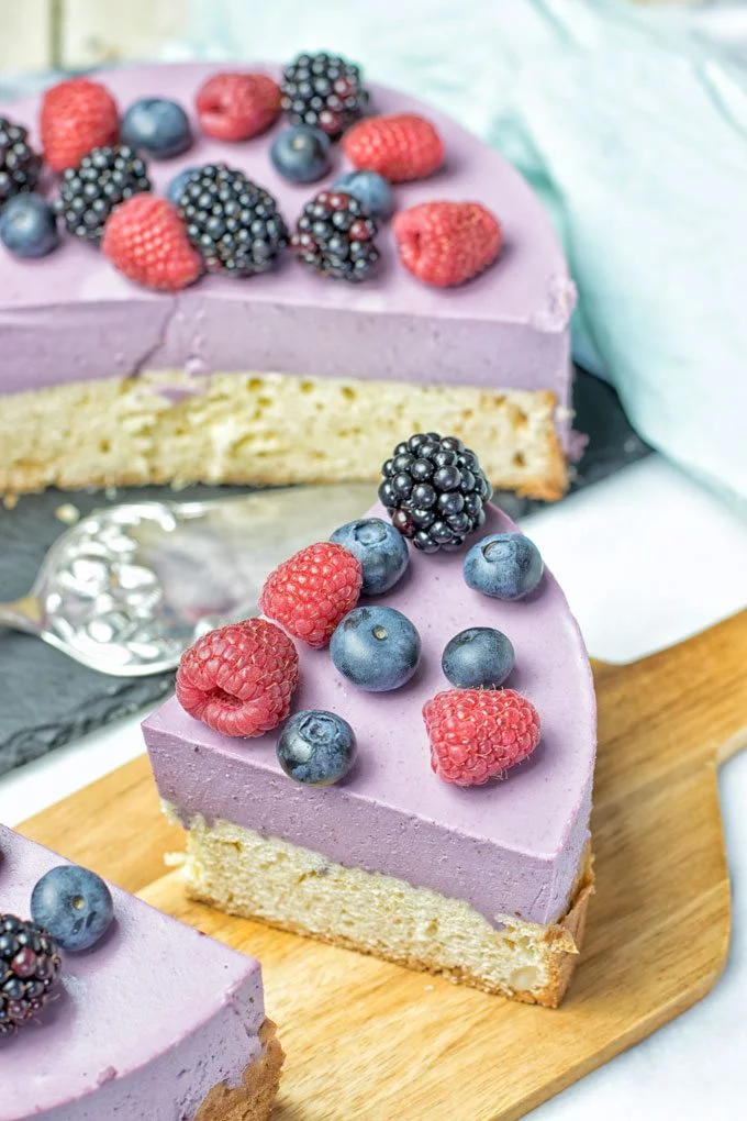 Two slices of the Berry Smoothie Yoghurt Cake on a wooden board.