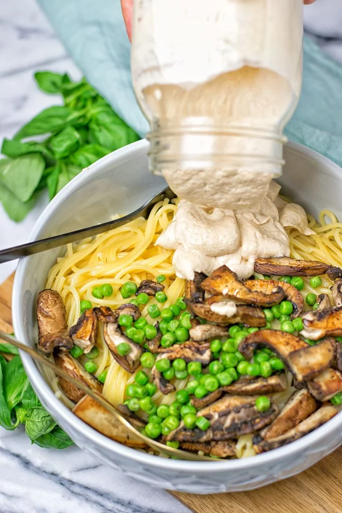 Pouring the Spicy Tahini Pasta Sauce over pasta