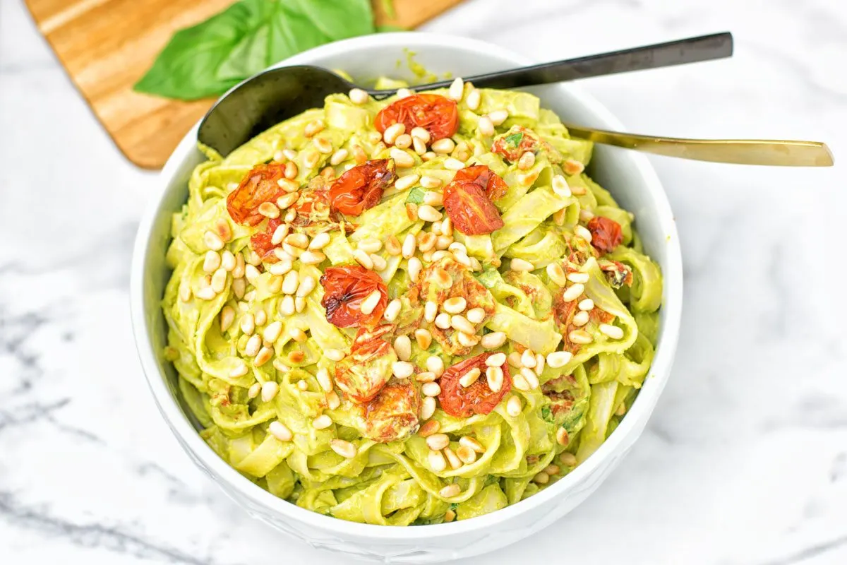 A large bowl of Avocado Pesto Pasta with a black and golden spoon.