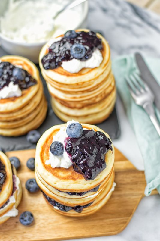 Three pancake stacks with blueberry jam and vegan ricotta.
