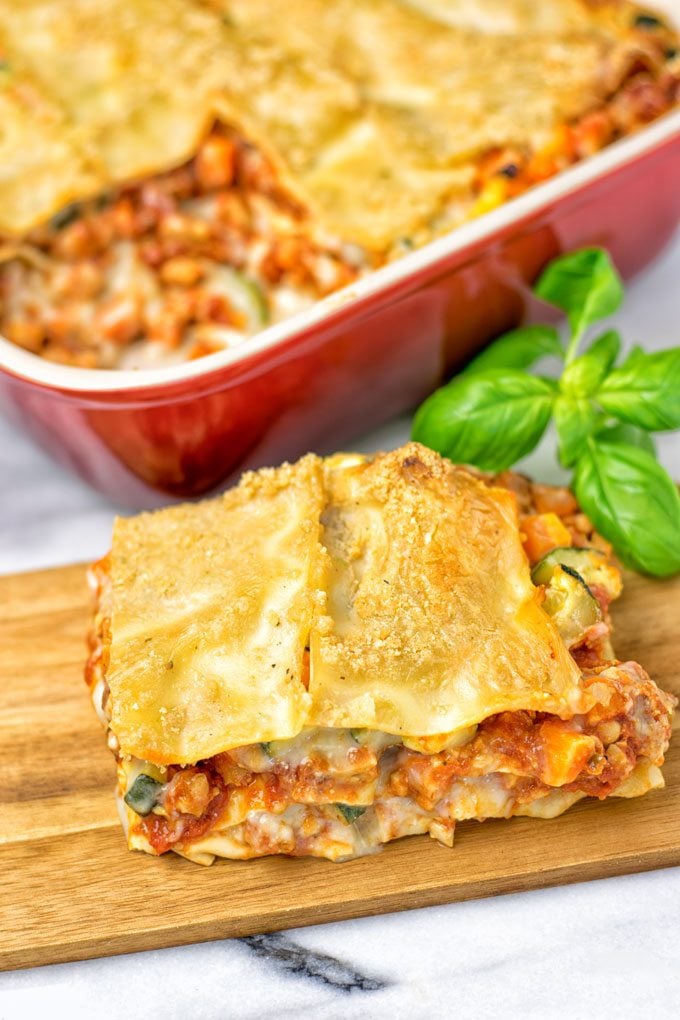 A piece of the Creamy Carbonara Vegetarian Lasagna on a wooden board. 