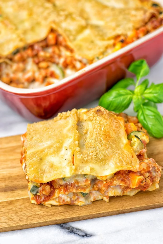 A piece of the Creamy Carbonara Vegetarian Lasagna on a wooden board. 