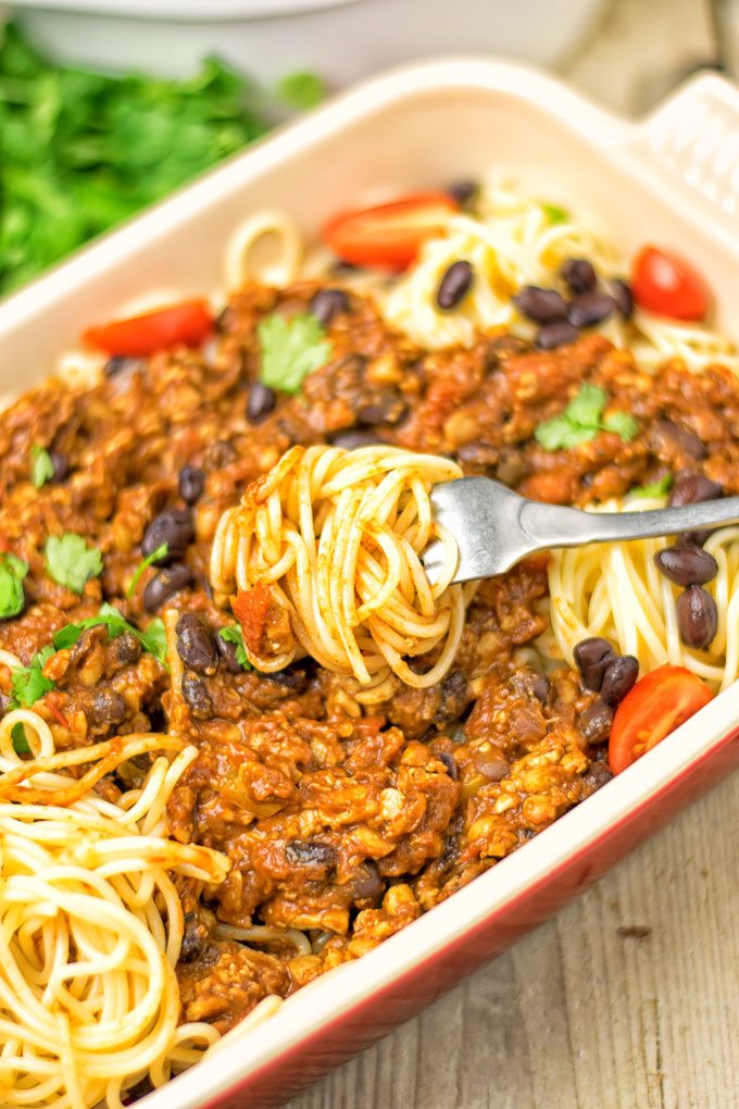 A fork lifting pasta out of the casserole dish.