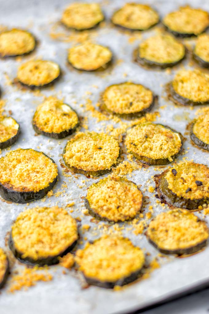 This Baked Zucchini Parmesan is entirely vegan, gluten free and will be a family favorite. Serve it with pasta, dips, as appetizer, dinner, lunches, meal preparation, or work lunch. Sprinkled with the best dairy free parmesan cheese that makes all the difference. Try it now. #vegan #dairyfree #vegetarian #contentednesscooking #dinner #lunch #mealprep #worklunchideas #zucchiniparmesan #zucchiniparmesanbaked #zucchiniparmesancrisps #comfortfood #kidfriendlydinners #familydinnerideas 