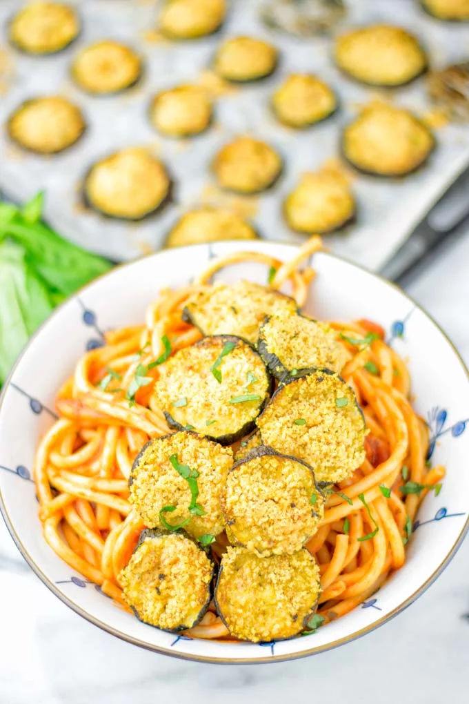 This Baked Zucchini Parmesan is entirely vegan, gluten free and will be a family favorite. Serve it with pasta, dips, as appetizer, dinner, lunches, meal preparation, or work lunch. Sprinkled with the best dairy free parmesan cheese that makes all the difference. Try it now. #vegan #dairyfree #vegetarian #contentednesscooking #dinner #lunch #mealprep #worklunchideas #zucchiniparmesan #zucchiniparmesanbaked #zucchiniparmesancrisps #comfortfood #kidfriendlydinners #familydinnerideas 