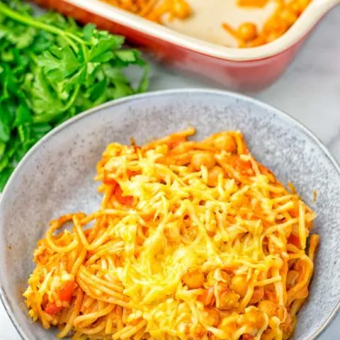 Baked vegan casserole portion in a bowl, covered with melted cheese.