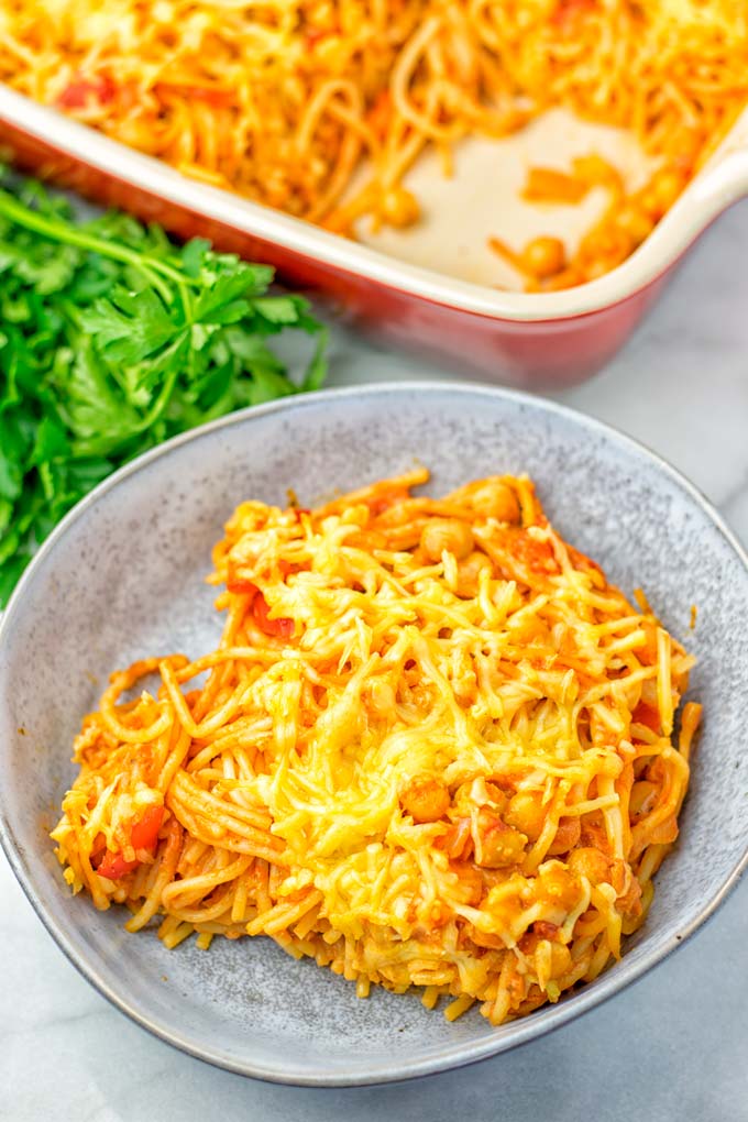 Baked vegan casserole portion in a bowl, covered with melted cheese.