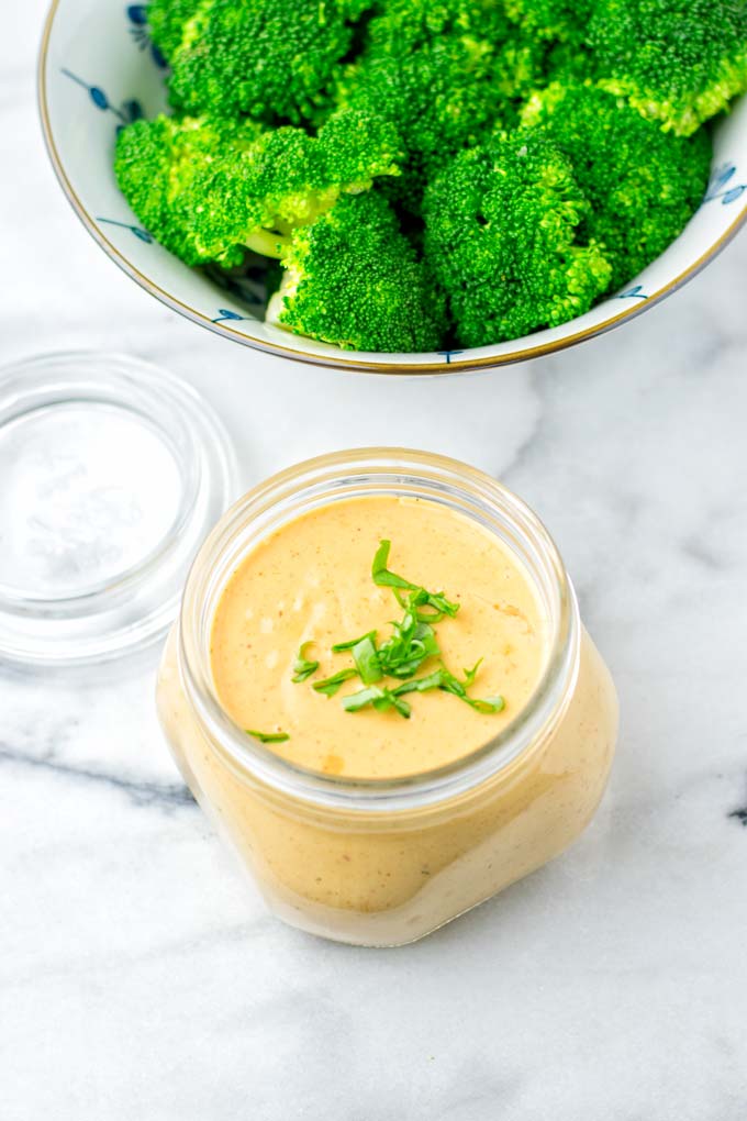 Thai Peanut Sauce in a jar with broccoli in the background. 