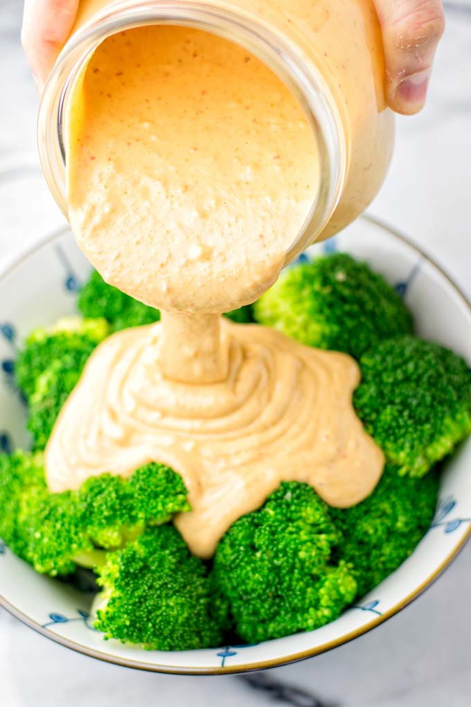 Thai peanut sauce poured over a bowl with broccoli. 