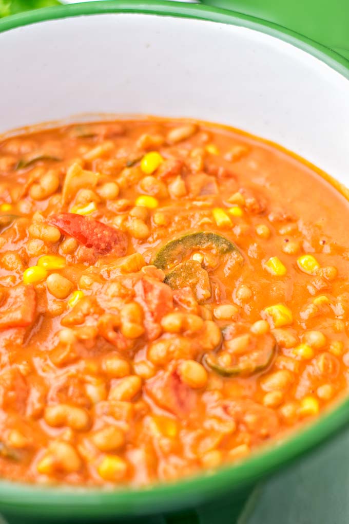 Closeup of vegetarian white bean chili cooking in a green pot.