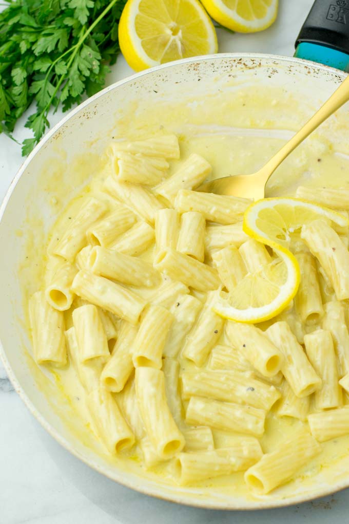 Pan full of pasta with sauce and a golden spoon.