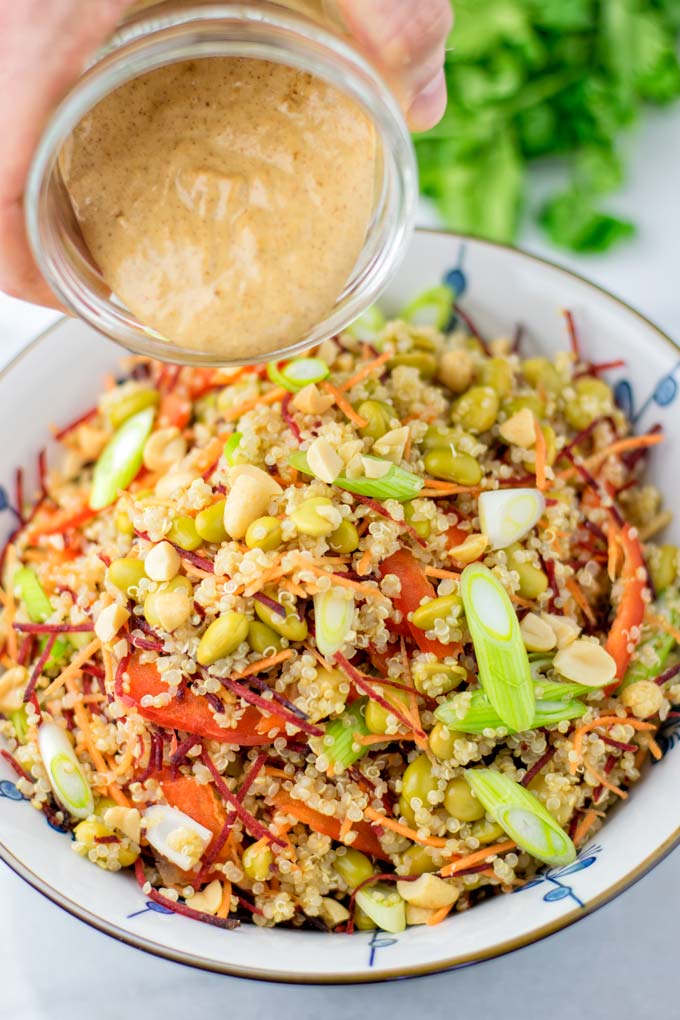 Poring the Thai Peanut Sauce over the quinoa salad.