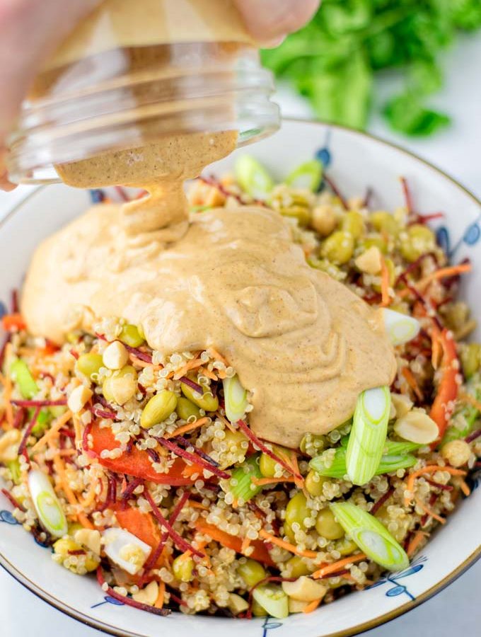 Poring the Thai Peanut Sauce over the quinoa salad.