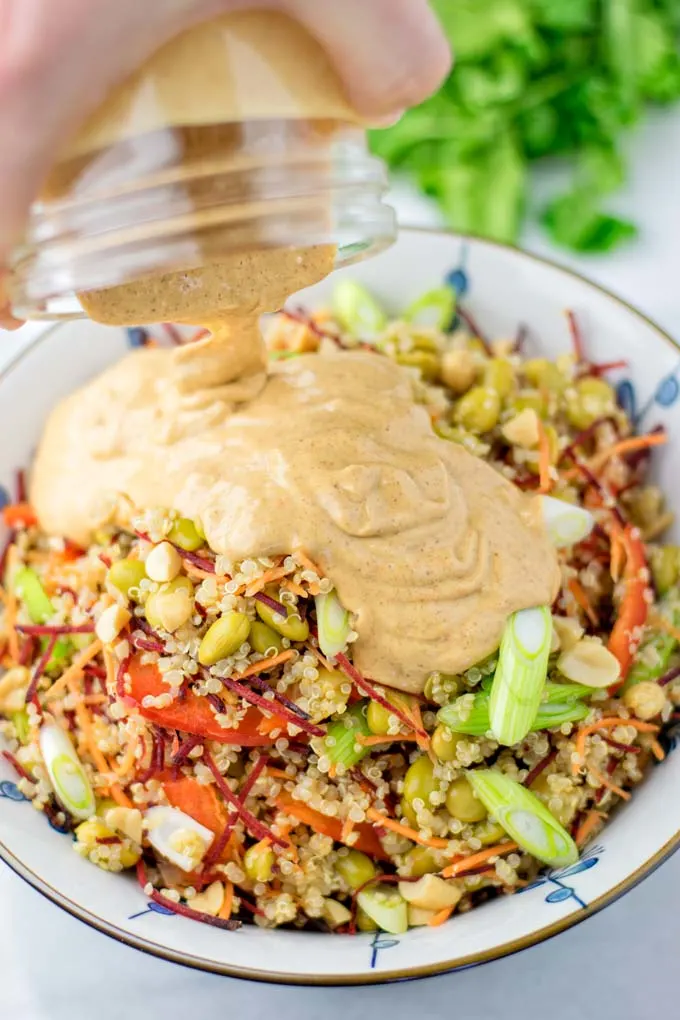 Poring the Thai Peanut Sauce over the quinoa salad.