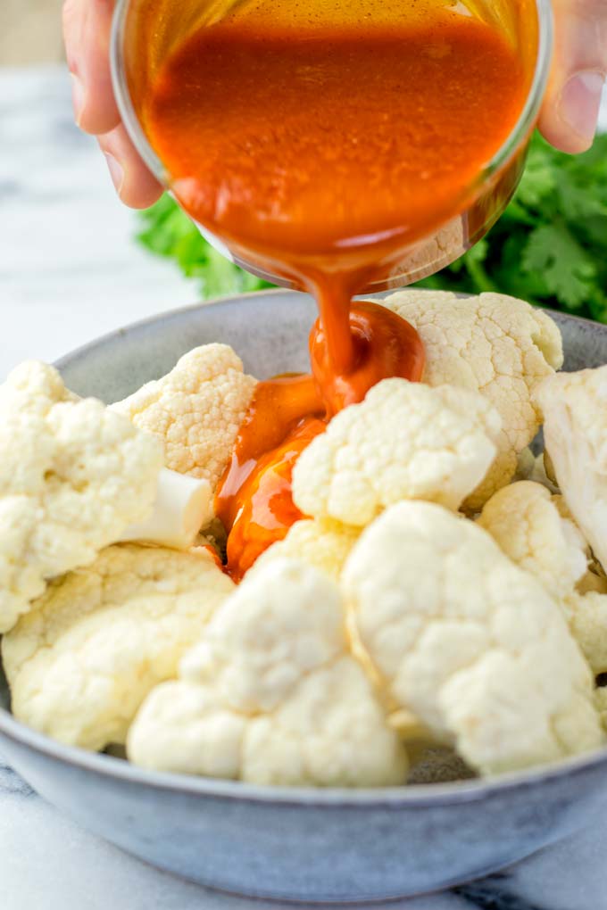Pouring the Buffalo Sauce over Cauliflower.